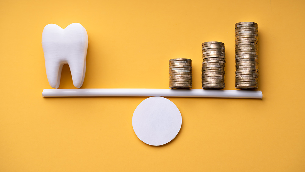 A tooth and coins balance on each end of a see-saw